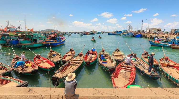 A traditional fishing village with thatched cottages, colorful boats, and warm locals.