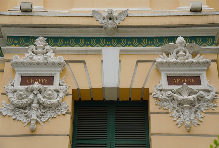 The names of renowned scientists are etched into rectangular panels that adorn the building's exterior.