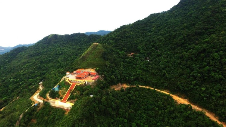 Stunning aerial view of Thai Thuy Temple on lush green mountain in Vietnam, surrounded by dense forest.