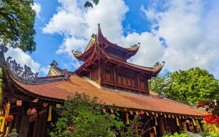 Ornate traditional Vietnamese temple with red tiled roof and lush greenery in Vietnam.