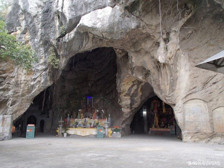 Sacred cave temple with altar and religious statues in natural limestone cavern in Vietnam.