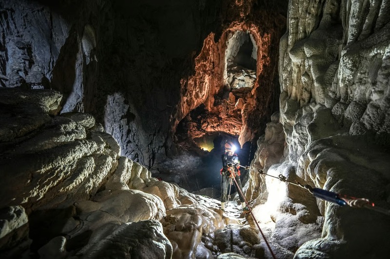 Participants on a Son Doong cave trek climbing the Great Wall of Vietnam with harnesses and ropes