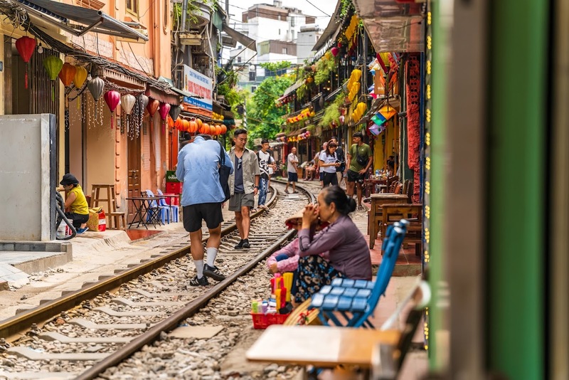 Hanoi train passing closely between cafés and homes along the railway corridor
