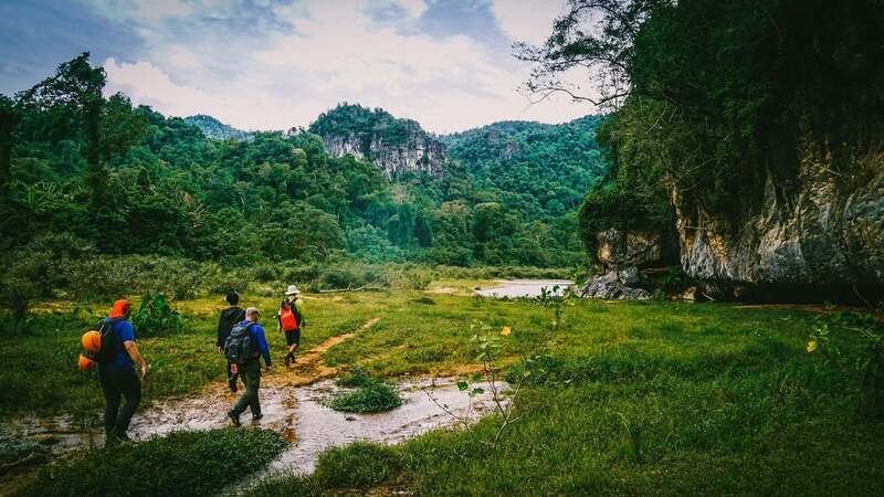 Son Doong Cave Tour adventurers trekking through the jungle toward Ban Doong Village and Hang En Cave